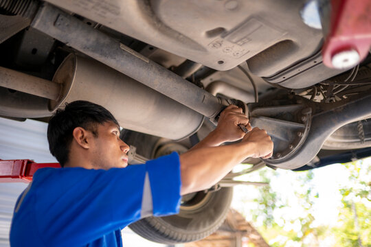 Auto mechanic examining car undercarriage for repair at garage