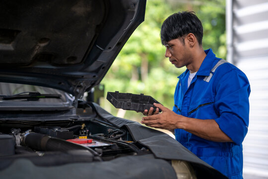 Auto mechanic checking car engine fuse box