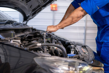 Auto mechanic repairing car engine with wrench