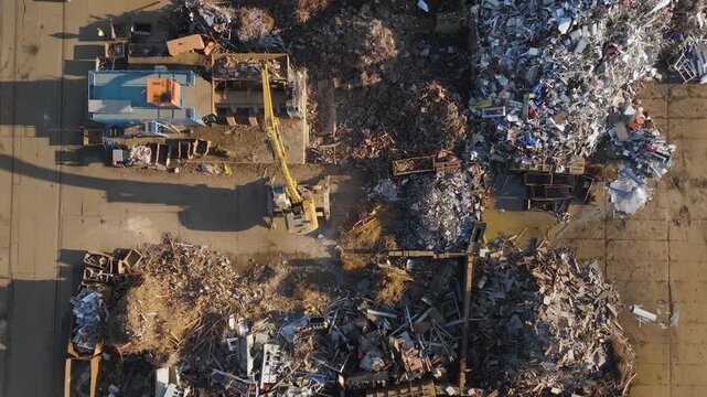 Aerial view of industrial scrapyard with excavators sorting metal debris