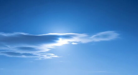 A serene blue sky with soft clouds and the sun peeking through them