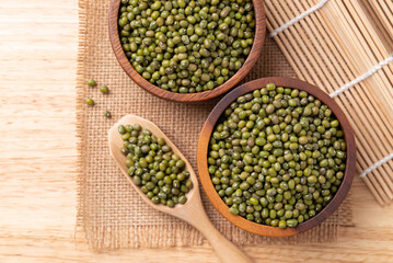 Mung bean in wooden bowl and scoop on wooden background, Asian food ingredient, Table top view