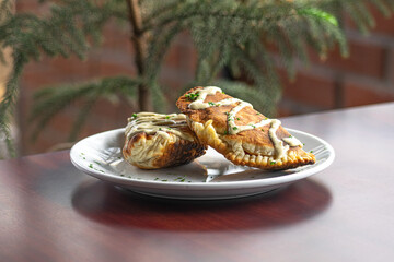 Food photography of two empanadas with sauce placed on a white plate