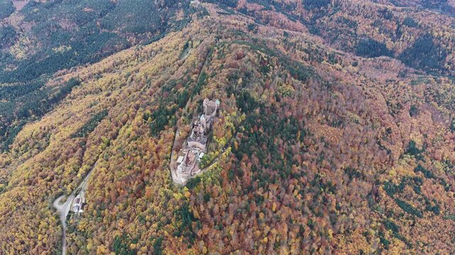 Aerial view of Haut-Koenigsbourg castle amid autumnal foliage, a medieval fortress atop a hill, contrasting textures, Orschwiller, Grand Est, France.