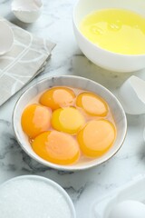 Broken eggs, yolks, whites and sugar on white marble table, closeup