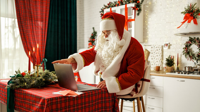 Santa Claus video calls on laptop in a festive Christmas kitchen setting
