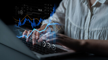 A business professional uses a laptop to analyze financial data, surrounded by digital graphs and...