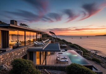 Breathtaking luxury villa with infinity pool on a rugged cliffside overlooking the ocean at sunset