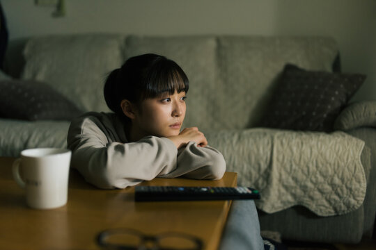 電気を消してテレビを観る若い女性