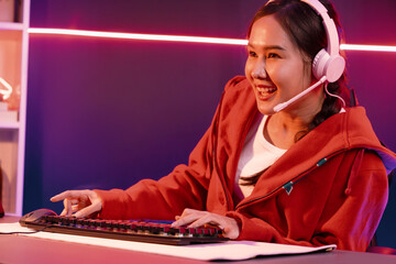 Host channel of smiling beautiful Asian girl streamer playing online game wearing headphone talking...