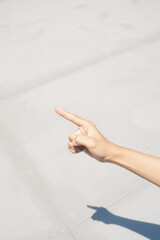 Close-up of a hand pointing towards the right, casting a shadow on a concrete surface.