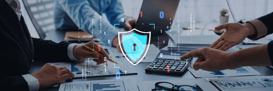 Business professionals engage in a discussion on cybersecurity strategies while analyzing data analytics. Digital security icons highlight importance in a modern office setup. Trope