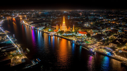 Obraz premium Aerial night view of Wat Arun temple illuminated with colorful lights along Chao Phraya River in Bangkok Thailand