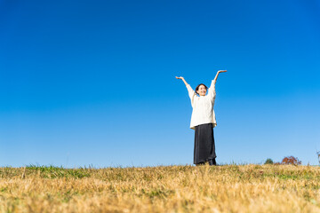 丘の上で腕を伸ばしている女性 ライフスタイルイメージ