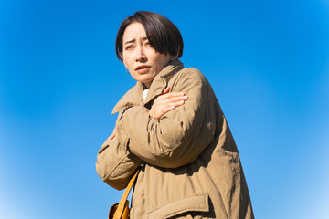 Fototapeta premium 冬空に凍える女性 ライフスタイルイメージ