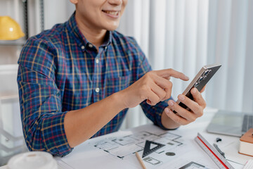 A young male architect is working with blueprints at his desk, using rulers and drawing tools to refine details. He appears focused and engaged, balancing creativity with precision.