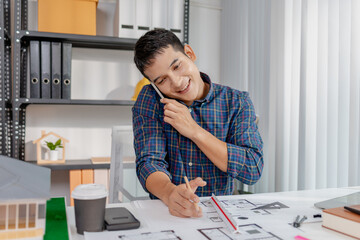 A young architect is multitasking at his desk, sketching blueprints, making phone calls, and reviewing notes. His workspace shows focus, productivity, and modern design work.