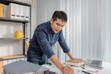 A young architect is multitasking at his desk, sketching blueprints, making phone calls, and reviewing notes. His workspace shows focus, productivity, and modern design work.
