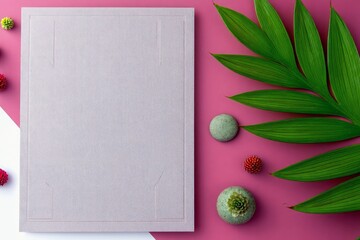 A flat lay composition featuring a textured purple card, lush green leaves, and small decorative round objects on a bright pink surface.