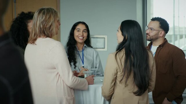 A group of professionals engage in conversation and networking at a conference or business event. They are smiling and interacting, fostering connections in a pleasant atmosphere.
