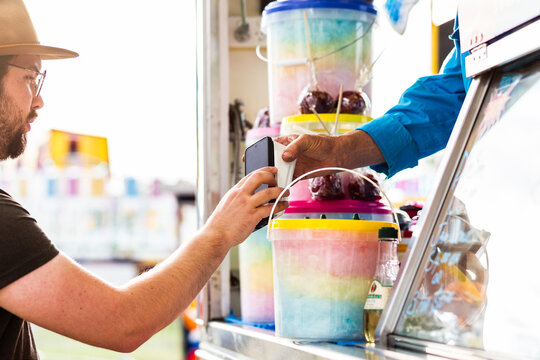Man buying bucket of fairy floss from sideshow alley stall at local show event