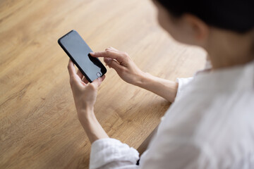 Close-Up of Hands Operating Smartphone on Wooden Table