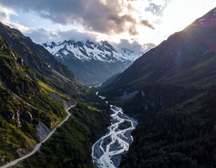 Aerial view of a winding road along a river through snowy mountains