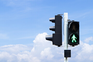 Traffic lights with green or red light lit hanging on steel pole with blue sky cloud white is background. Safety with people to travel. Sign or symbol icon pedestrians not allowed crossing road. 