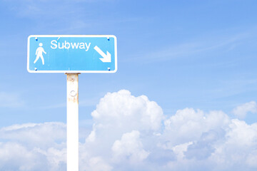 Signs blue rectangle aluminum with white letters subway, arrow and pedestrian icon with blue sky cloud white is background. Provides directions to underground metro station sign.