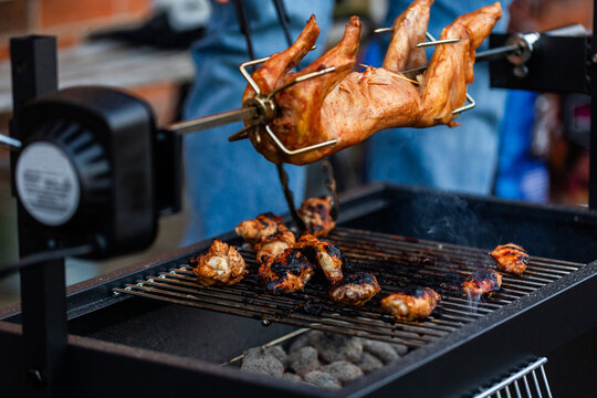 cooking chicken over charcoal fire pit grill in backyard