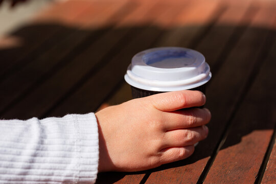 Child with baby chino in takeaway cup on caf&eacute; table