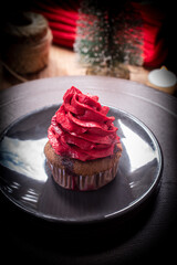 Delicious chocolate cupcakes topped with red buttercream, served on a ceramic plate with a warm festive atmosphere. Perfect sweet dessert for Christmas and New Year celebration.