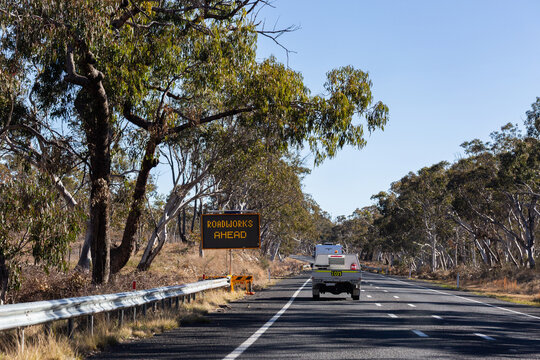 road work ahead sign and vehicle driving along rural highway in NSW Australia