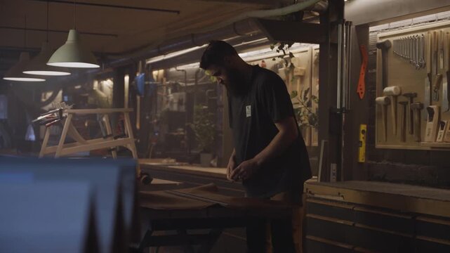 A craftsman works carefully with a large sheet of leather in a workshop filled with tools, showcasing precision, craftsmanship, and traditional leatherworking techniques.