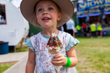 Little kid eating ice cream at showground event
