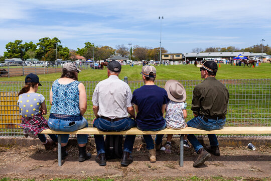 Aussie family with children and parents sitting around showground ring watching horse events