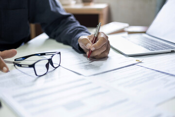 asian businessman using tablet computer working online at home with documents and taking note to create work schedule