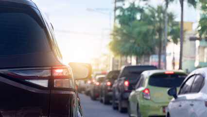 Rear side of car with turn on brake light. Cars parked in long lines in the city. Green ornamental...