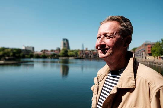 Senior man enjoying view of cityscape across water on sunny day