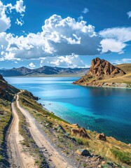 Turquoise lake, rocky shore, dirt road, puffy clouds, sunny