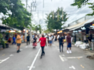 blurred view of people and a busy crowd walking down a street in an outdoor market