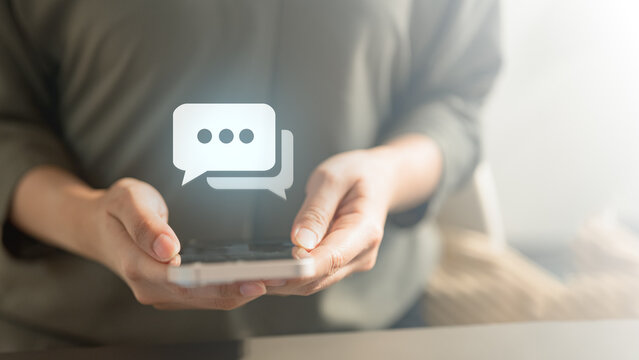 message, chat, messaging, texting, online, app, Close-up of hands holding a smartphone with a chat bubble icon, representing online messaging and digital communication.