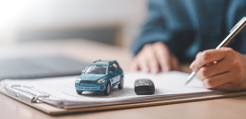 car, loan, purchase, insurance, finance, Close-up of a car model and key on a contract document with a person signing, representing car loan, vehicle finance, and insurance agreement.