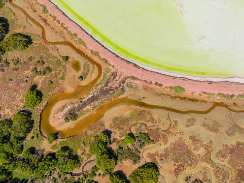 Aerial view of a stream and embankment around colourful water in a salt lake