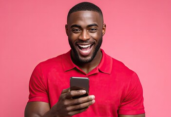a man in a red polo shirt appears excited while looking at his phone, isolated on a pink background