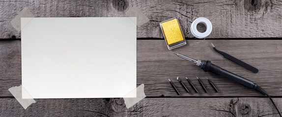 Blank Paper Sheet with Adhesive Tape on Wooden Rustic Table with Soldering Iron and Solder. File with Clipping Path.