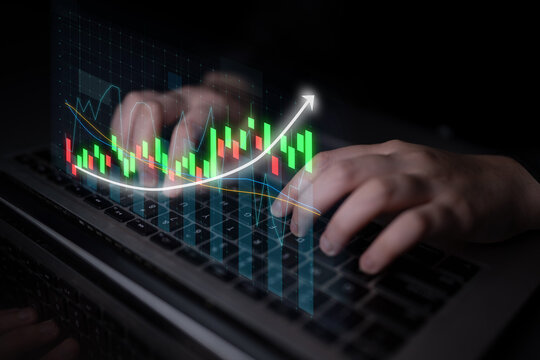 A close-up view of hands typing on a laptop with vibrant stock market charts displayed on the screen, symbolizing the dynamic world of financial trading and analysis. Impute