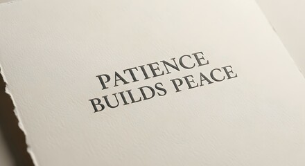 A close-up of a white paper with the inspirational quote 'Patience Builds Peace' printed in bold black letters, emphasizing calmness and mindfulness