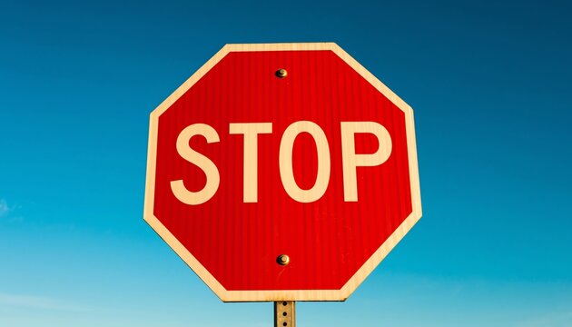 Red stop sign blue sky, octagonal warning symbol for traffic safety, clear weather, road caution, transportation, and regulatory message on a sunny day.