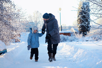 Family with children play snowy winter games in the park. Winter holidays and family vacation....